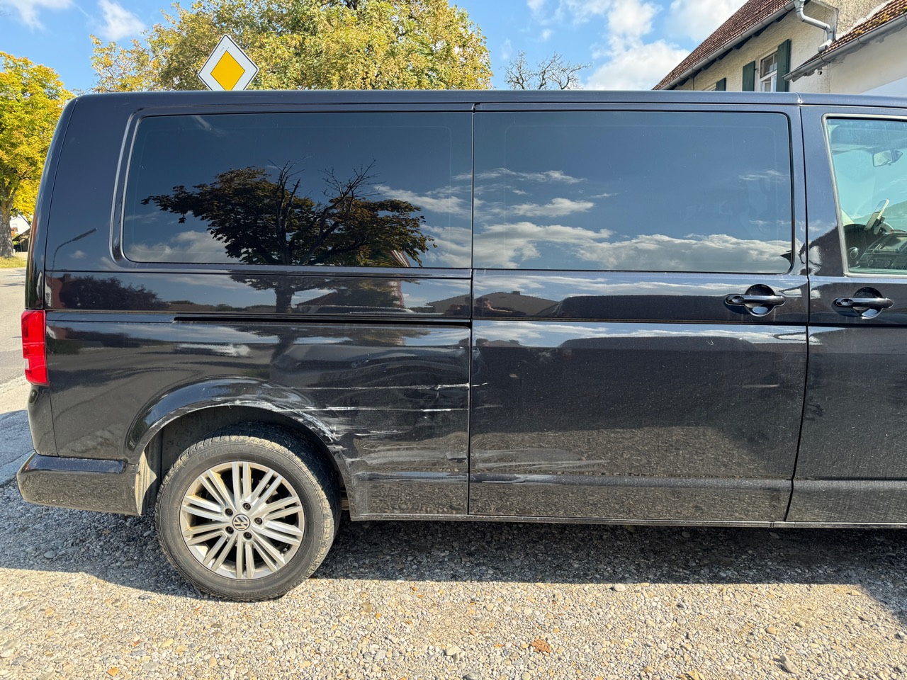 Seitenübersicht eines VW Caravelle mit Schürfspuren an Schiebetür und hinterem Radlauf